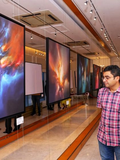 Visitors engrossed in the details of Simon Kenny's large-scale abstract paintings at 'Mystic Mirage'.