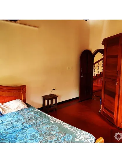 A bedroom in the Udupi house, showcasing the rich color of the wooden wardrobe and the natural light from the window. Our designs prioritize simple, well-crafted spaces that are comfortable and timeless.