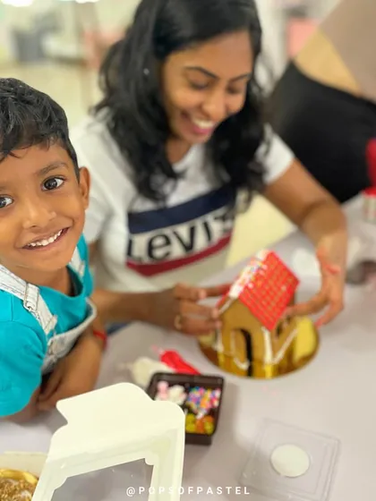 The smile of a happy little builder. This young boy is having a great time decorating his gingerbread house.