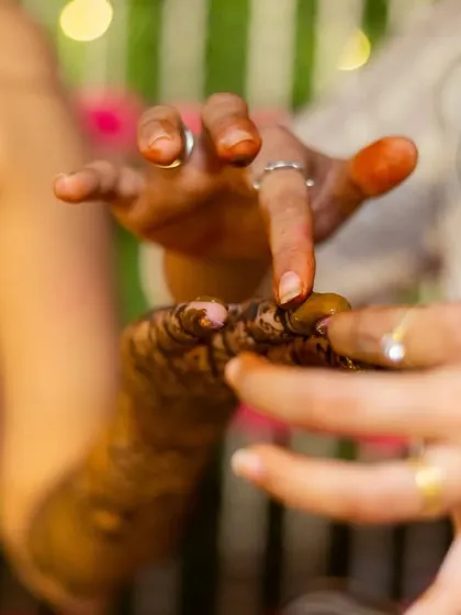 A close-up of the mehendi application in progress, showing the artist's steady hand and the fresh henna paste.