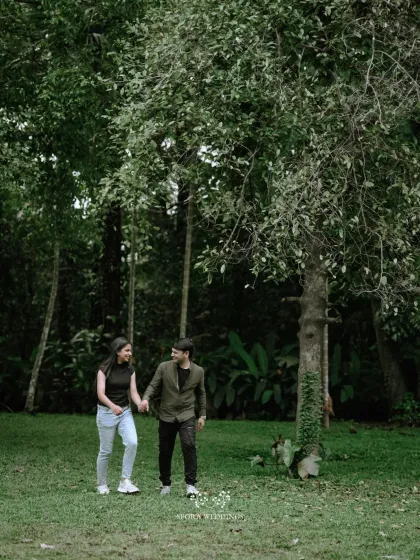 The couple taking a romantic stroll through a park, hand-in-hand, enjoying a quiet moment together.