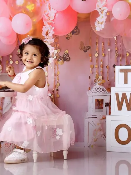 A two-year-old girl playing a mini piano in a beautiful pink-themed setup for her birthday.
