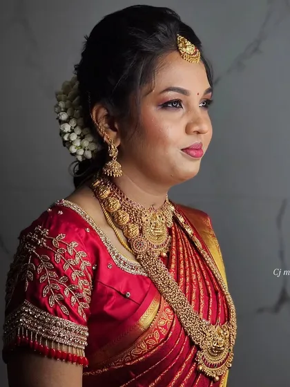 A close-up of a flawless and radiant muhurtham makeover, with a beautiful red saree and gold jewelry.