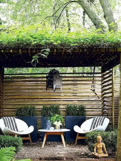 A beautiful example of a shaded Zen garden. The space features a rustic bamboo pergola, comfortable seating, and a small Buddha statue, creating a perfect spot for quiet contemplation.