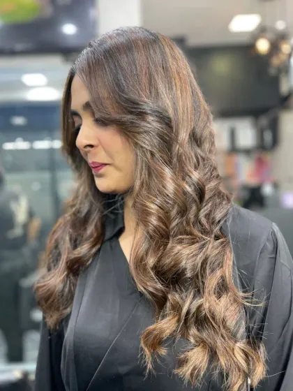 A sophisticated look with medium-length hair styled in perfect, glossy curls with subtle highlights.