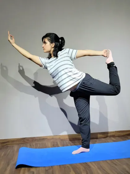Holding the dancer's pose, or Natarajasana. This is a challenging balance pose that improves focus while stretching the shoulders, chest, and thighs. It's a perfect blend of grace and strength.