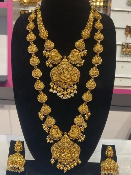 This temple jewellery set showcases detailed carvings of deities on both the choker and the long necklace, accented with small pearls.