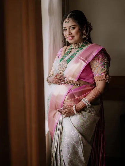 We specialize in traditional maternity photoshoots, celebrating cultural heritage with grace. This portrait captures the expectant mother's serene glow, beautifully framed by natural window light that highlights the intricate details of her silk saree and jewellery.