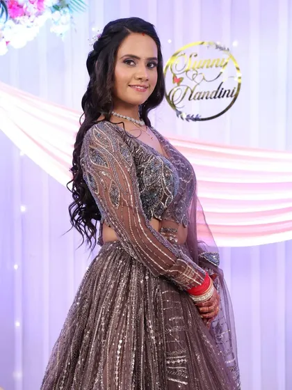 A full-length view of the reception bride in her shimmering lehenga. The makeup is designed to complement the sparkle of her outfit, with a focus on glowing skin.