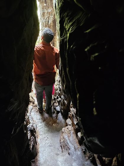 Navigating a narrow passage between two rock walls inside the caves.