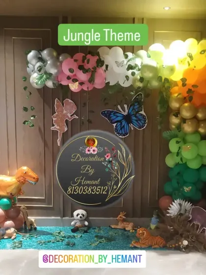 A detailed photo wall for the jungle theme party. This setup includes various animal cutouts like a dinosaur, tiger, and deer, set against a backdrop of green and colorful balloons to create a vibrant forest scene.