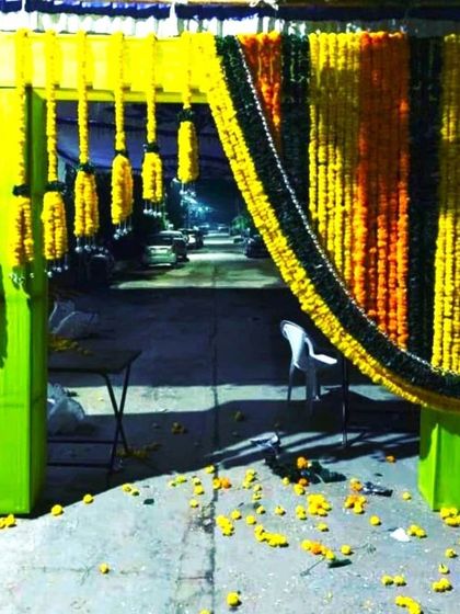 An entrance flower decoration for a wedding. The archway is heavily decorated with yellow and orange marigold garlands for a traditional and grand welcome.