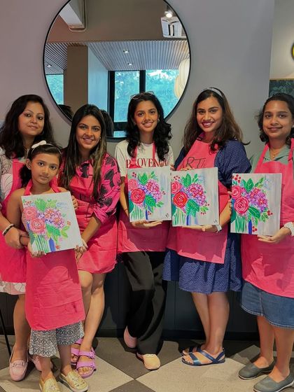 A group of women and a young girl with their floral paintings. It's a lovely mother daughter activity or a fun outing for friends.