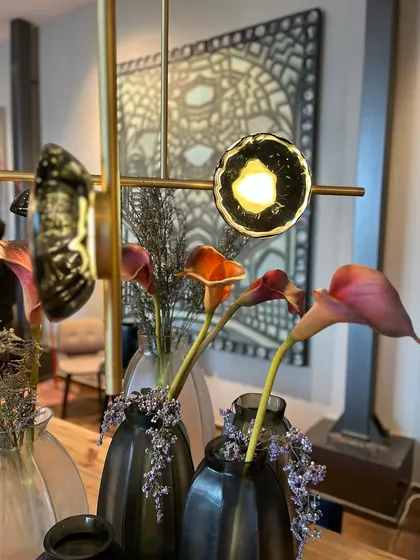 An artistic shot of the Ceto chandelier with flowers in the foreground, emphasizing the organic inspiration behind the design.
