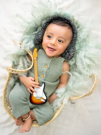 A sweet overhead shot of this baby boy, ready to play his guitar.