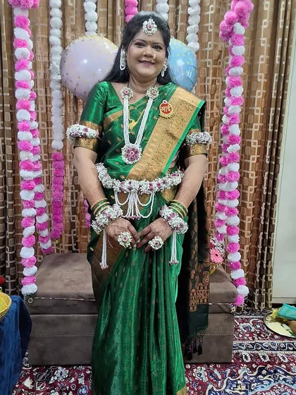 A full-length view of the baby shower jewellery set, including the long necklace, kamarband, and bajuband. The 'Aai' medallion is pinned to her saree.