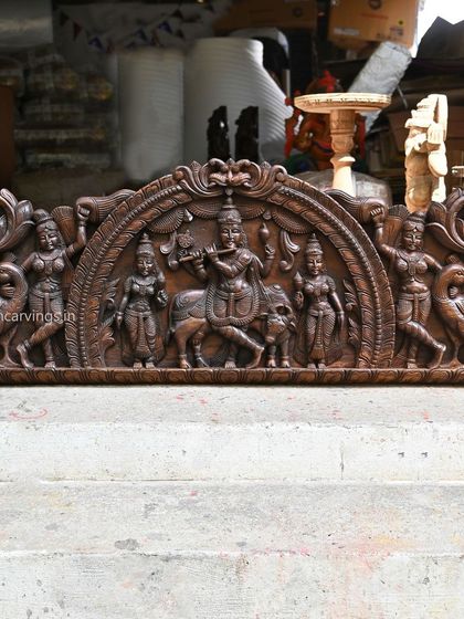 Our 54-inch Kirthi Mukh arch panel frames a serene scene of Lord Krishna playing his flute. The single-tone wood finish emphasizes the graceful forms of Krishna, his attendants, and the surrounding peacocks.