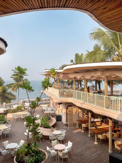 A high-angle view of Dubki, capturing the organic cutouts in the roof that frame the sky and palm trees. This design choice connects the space to its natural surroundings, enhancing the open, airy feel of this Goa beach club.