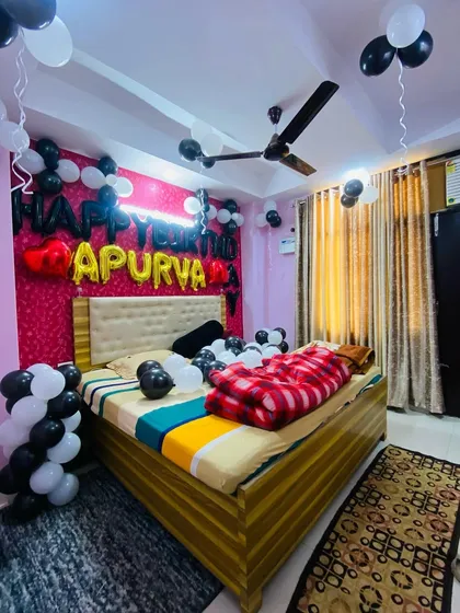 A simple bedroom decoration for a birthday, with black and white balloons on the ceiling and a personalized name banner over the bed.