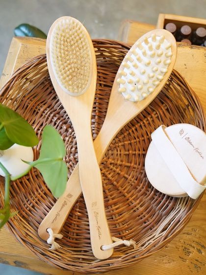 Soak, scrub, and shine. This collection of wooden body brushes and a soft exfoliating pad, resting in a wicker basket, has everything you need for an at-home spa day.