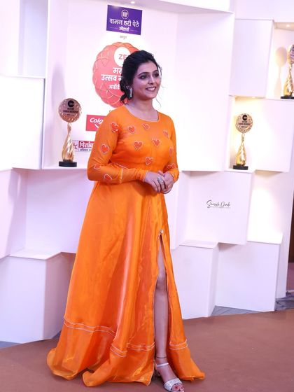 A full-length shot of Shivani at the Zee Marathi Awards party. She looks stunning in a vibrant orange gown with a thigh-high slit.