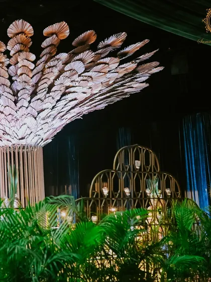 A sculptural tree with a canopy of fanned leaves stands as a unique art piece within the venue, surrounded by lush greenery to enhance the enchanted forest feel of the soirée.