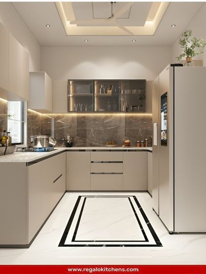 A clean and contemporary U-shaped kitchen in a soft beige. The design includes integrated appliances and glass-front cabinets. A decorative floor pattern adds a unique touch to the minimalist aesthetic.
