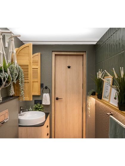 Even the bathrooms follow the home's natural, earthy theme. This powder room combines green handmade tiles with a wooden vanity and charming window-shutter mirror for a rustic-chic feel.