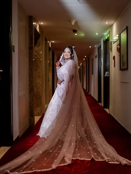 A dramatic full-length portrait of a bride, her incredibly long veil trailing behind her on a red carpet.