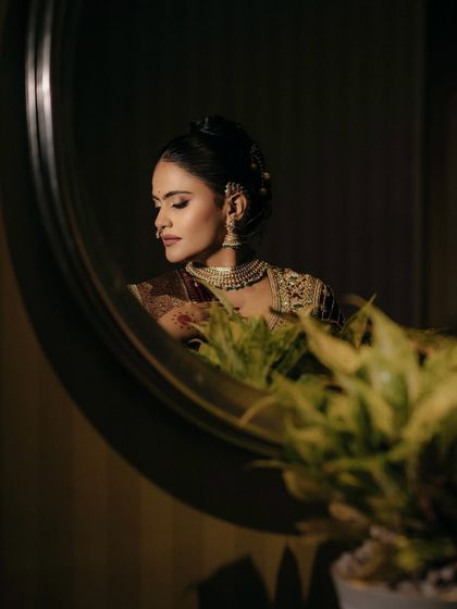 A moment of quiet reflection. The mirror captures the soft yet defined makeup, with contoured cheeks and beautifully shaped brows that frame her face perfectly.