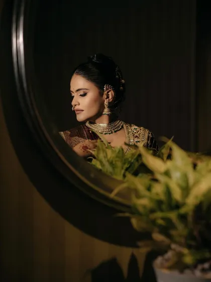 A moment of quiet reflection. The mirror captures the soft yet defined makeup, with contoured cheeks and beautifully shaped brows that frame her face perfectly.