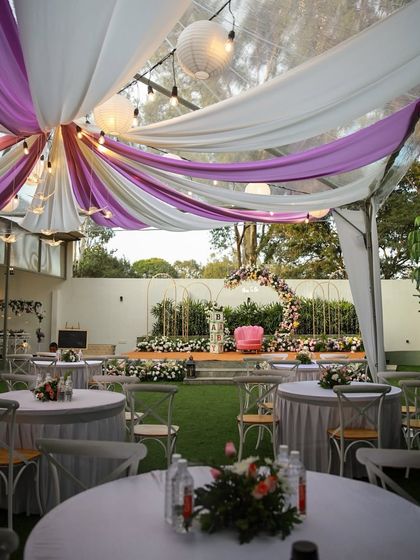 An intimate baby shower setup at The Backyard. The purple and white draping under the clear-top tent creates a soft and elegant atmosphere for the celebration.