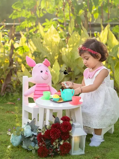 Pouring tea for her friend Piglet. This imaginative play during her second birthday shoot shows her sweet and caring personality.