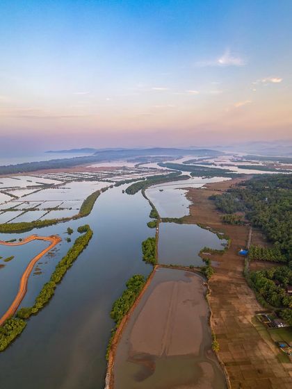 A vast aerial panorama of the Aghanashini river delta in Kumta. This shot, taken from a spot known only to locals, reveals the intricate network of waterways used for salt making and marine activities.