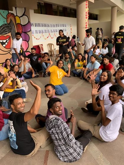 A circle of friends. Participants sit together at Sign Fest, waving and smiling. This image captures the sense of community and belonging we foster at our events.