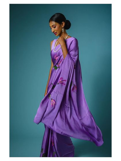 The movement of the fabric is captured in this shot, showing the light and airy quality of the purple saree. Dynamic shots like this add interest to a product gallery.