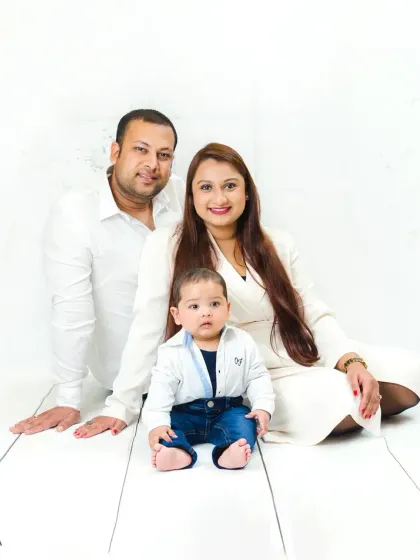 A lovely seated family portrait. The baby takes center stage while the parents look on with love, creating a balanced and heartwarming composition.