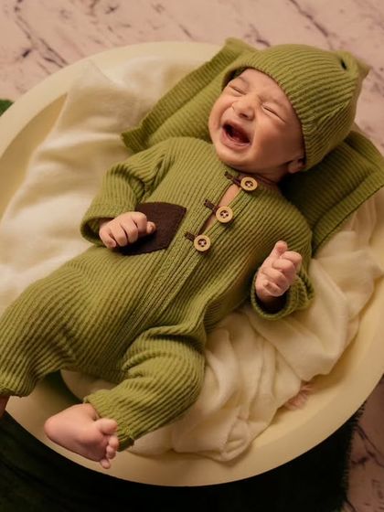 Capturing a real moment, this photo shows a newborn crying while lying in a bowl, showing the authentic side of baby photography.
