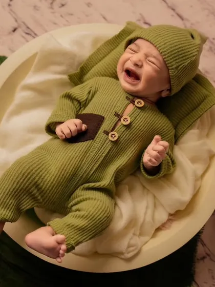 Capturing a real moment, this photo shows a newborn crying while lying in a bowl, showing the authentic side of baby photography.
