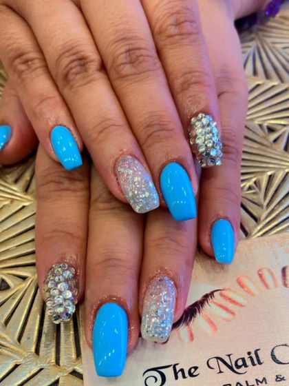 Stand out with these vibrant sky blue nails in a square shape. The set includes accent nails fully covered in silver glitter and others with dense, 3D-style silver crystal work for maximum impact.
