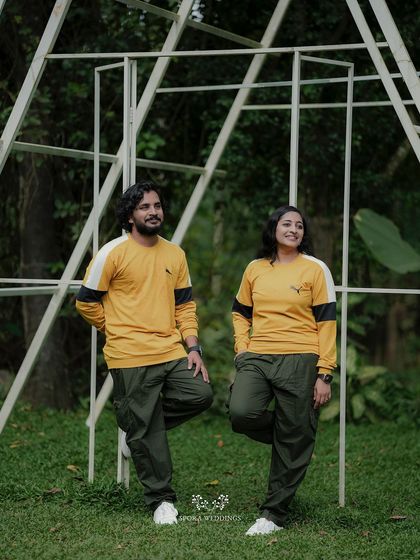 The couple posing against a modern, white triangular structure, their casual outfits and relaxed poses creating a cool vibe.