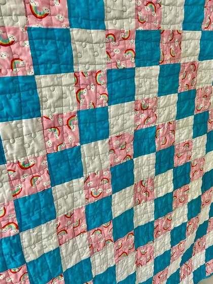 A close-up of the rainbow-themed fabric used in the quilt.