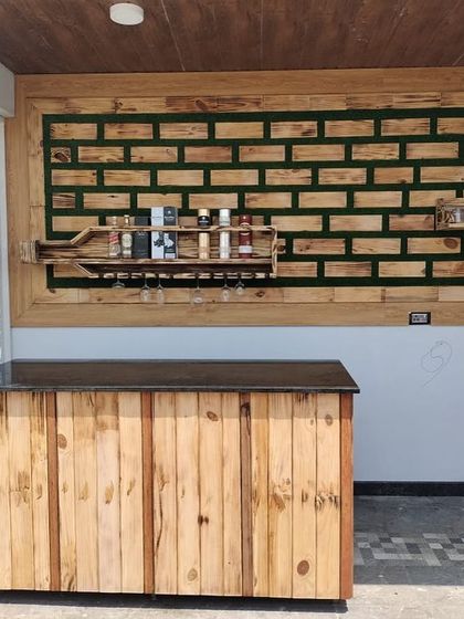 The full context of the outdoor bar area I designed. The custom wooden counter and wall art are complemented by the natural light and decorative privacy screen, making it a complete entertainment space.