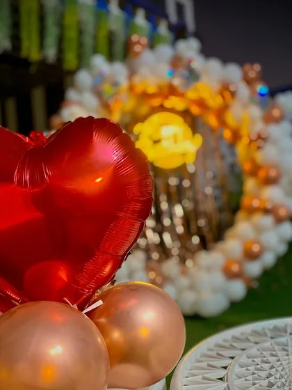A close-up shot of the details in my outdoor setups. Here you can see a bright red heart-shaped foil balloon, which adds a pop of color to the elegant white and bronze balloon arrangement.