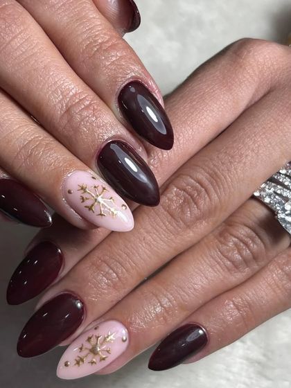 A sophisticated Christmas look. I paired a deep, glossy maroon polish with soft pink accent nails featuring delicate golden snowflake designs.