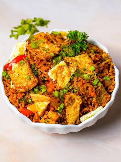 A vibrant bowl of fried rice loaded with crispy toppings and fresh herbs, shot from above on a light marble background. This angle and clean styling make it a great hero shot for a rice dish.