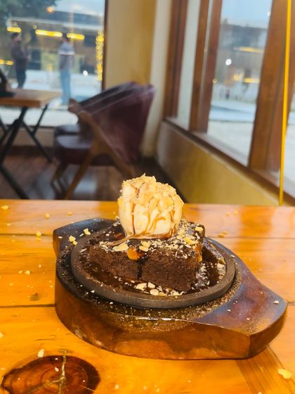 Our sizzling brownie, served hot on a wooden platter with a scoop of ice cream.