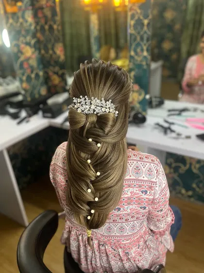 A beautiful half-up style with a bow and a pull-through braid, adorned with pearls.