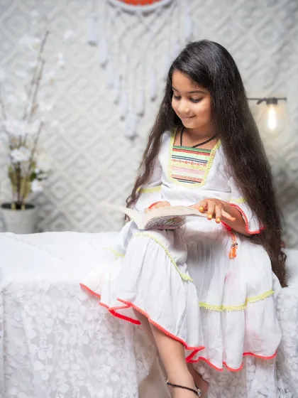A quiet, candid moment of a young girl lost in her book. The soft lighting and simple, bright setting create a peaceful mood. This portrait shows that even the calm, everyday moments can be beautiful and full of story.