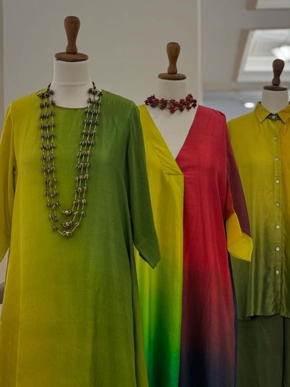 A display of stunning ombre-dyed dresses by Meghna Panchmatia, in vibrant shades of green, yellow, and red.